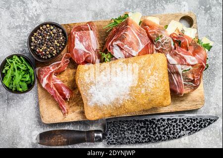 Ciabatta-Sandwich mit Schinken-Crudo-Schinken, Rucola und Camembert-Brie-Käse. Grauer Hintergrund. Draufsicht Stockfoto