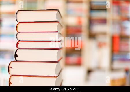 Gestapelte Bücher vor einem Bücherregal Stockfoto