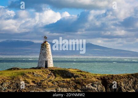 Der ursprüngliche Leuchtturm Twr Bach auf der Insel Llanddwyn mit schneebedecktem Snowdonia National Park im Hintergrund, Anglesey Stockfoto