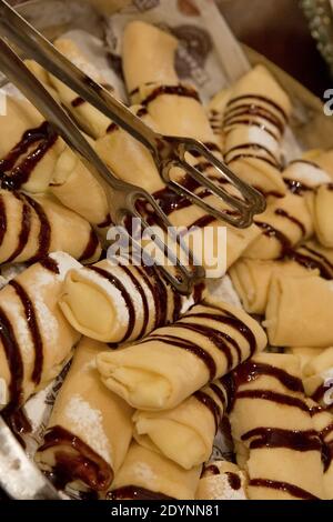 Süße Crepes garniert mit Schokoladensauce auf einem Buffettisch Stockfoto