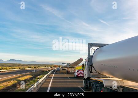 Spezieller Transport von Rotorblättern für Windenergieanlagen. Mehrere LKW mit Windturbinenblättern auf der Autobahn mit Beacon Fahrzeuge hinter anderen warnen Stockfoto