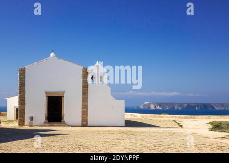 Kleine Kapelle Igreja de Nossa Senhora da Graça im Fort Sagres (Fortaleza de Sagres), Kap St. Vincent im Hintergrund die Algarve Portugal Stockfoto