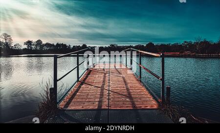 Ein hölzerner Dock blickt in einen kühlen Himmel über einem See in einem alten, verlassenen Golfplatz in Cape May, New Jersey. Stockfoto