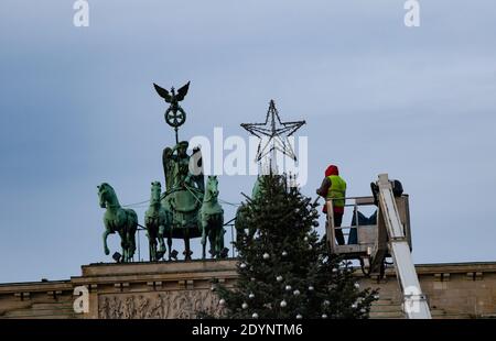 Berlin, Deutschland. Dezember 2020. Ein Arbeiter entfernt Dekorationen vom Weihnachtsbaum vor dem Brandenburger Tor. Quelle: Paul Zinken/dpa/Alamy Live News Stockfoto