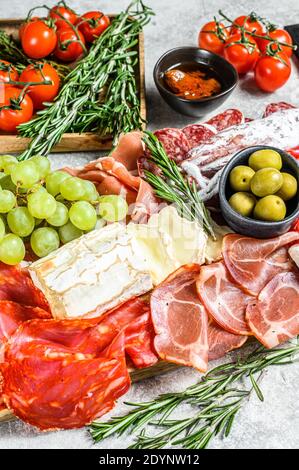 Antipasto Set Platte. Kalte geräucherte Fleischplatte mit Wurst, Schinken, Schinken, Speck, Oliven. Auswahl an Vorspeisen. Grauer Hintergrund. Draufsicht Stockfoto