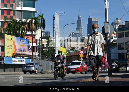 Kuala Lumpur, Malaysia. Dezember 2020. Ein Mann mit Gesichtsmaske geht auf einer Straße in Kuala Lumpur, Malaysia, 27. Dezember 2020. Malaysia meldete 1,196 neue COVID-19-Infektionen, teilte das Gesundheitsministerium am Sonntag mit und brachte die nationale Gesamtzahl auf 105,096. Quelle: Chong Voon Chung/Xinhua/Alamy Live News Stockfoto