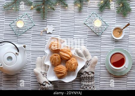 Kreative Xmas Tischaufstellung für Tee mit Kuchen. Kreative flache Lay mit leckeren eclairs oder Braukuchen. Weihnachtsbaum Form Teller mit Kuchen. Gestreifte Spitze Stockfoto