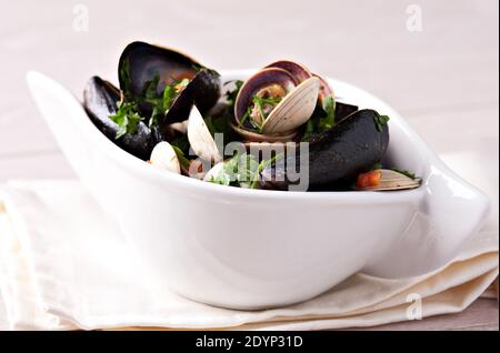 Vongole Seafood Muscheln mit Tomaten und Petersilie in einer Schüssel. Stockfoto