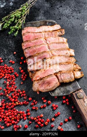 Gegrilltes Schweinesteak auf einem Fleischspalter. Bio-Fleisch. Schwarzer Hintergrund. Draufsicht Stockfoto