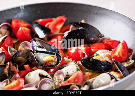 Vongole Seafood Muscheln mit Tomaten und Petersilie in Bratpfanne. Stockfoto