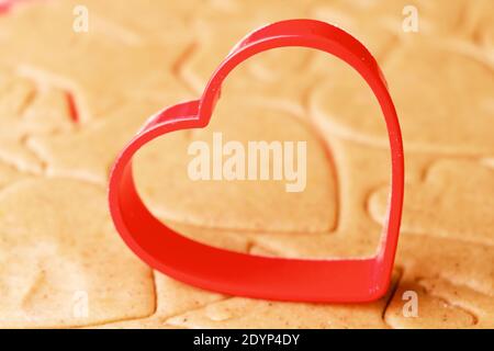Herzförmige Backform zur Herstellung von Lebkuchengebäck auf dem Teig. St. Valentines Süßigkeiten Stockfoto