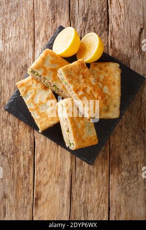 Mutabbaq ist ein köstlicher gefüllter Paratha mit würzigem Hackfleisch, das in Saudia-Arabien ein beliebtes Straßenessen ist, in der Nähe auf dem Tisch. ver Stockfoto