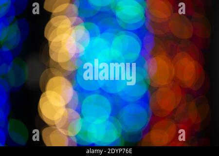 Mehrfarbige große Bokeh-Flecken in Blau, Gelb und Orange. Bokeh aus einer Weihnachtsgirlande. Stockfoto