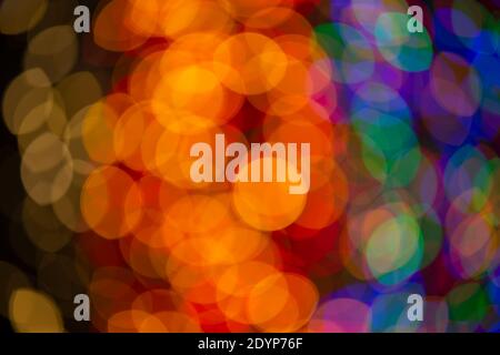 Mehrfarbige große Bokeh-Flecken in Blau, Gelb und Orange. Bokeh aus einer Weihnachtsgirlande. Stockfoto