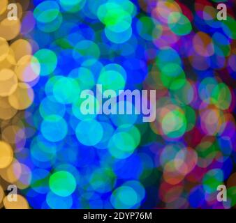 Mehrfarbige große Bokeh-Flecken in Blau, Gelb und Orange. Bokeh aus einer Weihnachtsgirlande. Stockfoto