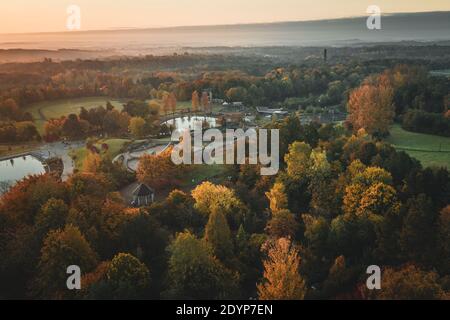 Luftaufnahme über landschaftlich schönen Spielplatz unter herbstlichen Bäumen bei Sonnenaufgang. Telford Centre Park in Großbritannien Stockfoto