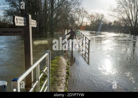 Oxford, Oxfordshire, Großbritannien. 27. Dezember 2020. Ein Mann erkundet die Themse. Die Fußgängerbrücke auf dem Themse-Pfad in Oxford ist überflutet. Überschwemmungen in Oxfordshire. Sturm Bella brachte noch mehr Regen nach Oxford und verursachte Überschwemmungen in tief liegenden Gebieten. Viele Menschen sind aus der Ausübung in der Sonne. Kredit: Sidney Bruere/Alamy Live Nachrichten Stockfoto