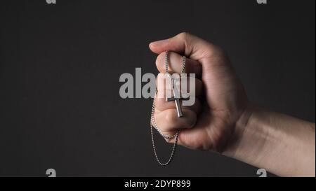 Kreuz oder Kruzifix Anhänger und Halskette in Mann Hand auf Schwarzer Hintergrund im Studio, die das Gebet für gott darstellen Oder jesus und Gott danken für giv Stockfoto