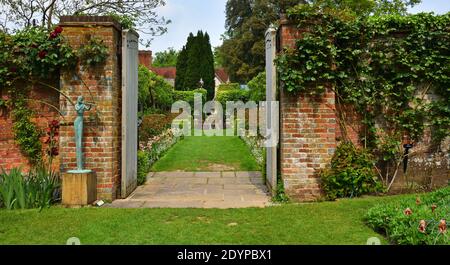 Gartentor mit Pflanzen und Statue. Stockfoto