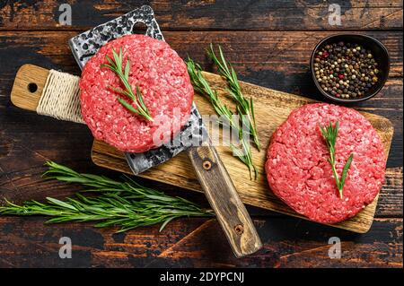 Hacksteaks aus rohem Fleisch gemahlen. Fleischschnitzel bereit zum Kochen. Bio-Fleisch auf dem Bauernhof. Dunkler Holzhintergrund. Draufsicht Stockfoto