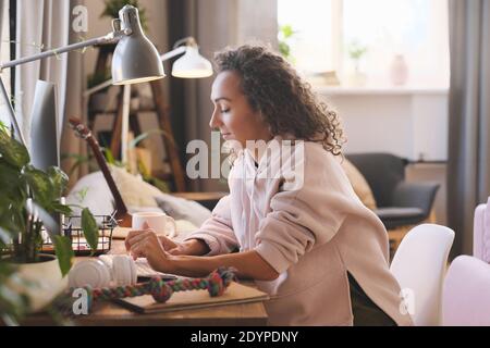 Junge Frau sitzt am Tisch und arbeitet online Computer zu Hause Stockfoto