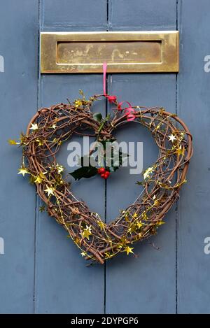 Weihnachten herzförmige Dekoration hängt von festlichen roten Band an einer Holztür in der malerischen Stadt Ludlow, Shropshire, England, Großbritannien. Stockfoto