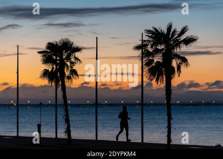 Ein Jogger, der am ersten Weihnachtsmorgen entlang der Strandpromenade in Southend on Sea, Essex, Großbritannien, läuft. Läufer am Meer vor Sonnenaufgang Stockfoto