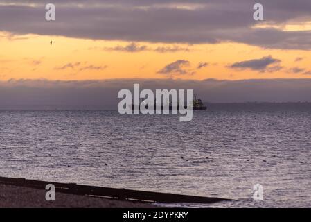 Schiff auf dem Weg zum Meer am Weihnachtsmorgen in Southend on Sea, Essex, Großbritannien. Schiff, das vor Sonnenaufgang im Winter in die Nordsee segelt Stockfoto