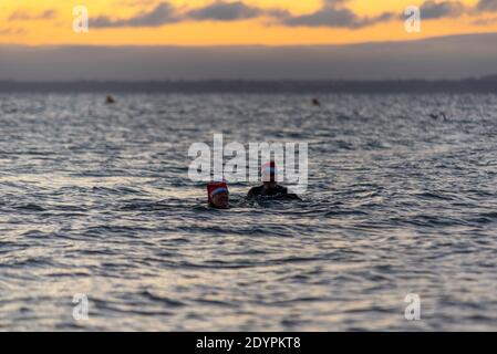 Kaltes Wasser Schwimmen in der Themse Mündung am Weihnachtstag Morgen in Southend on Sea, Essex, Großbritannien. Männer und Frauen tragen festliche Weihnachtsmützen Stockfoto