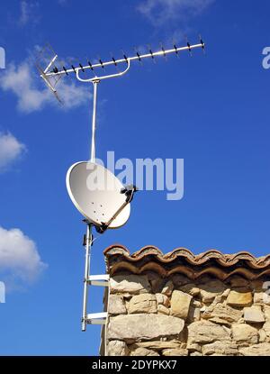 Antennenrechen und Parabolantenne auf einem alten Dach. Stockfoto