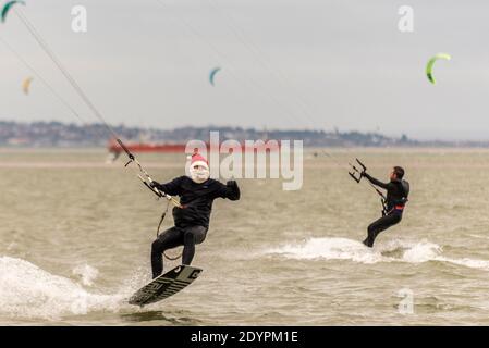 Kitesurfen am Boxing Day in Southend on Sea, Essex, Großbritannien. Männlicher Kite-Surfer trägt festlichen Weihnachtsmann Hut und weißen Bart, Springen aus dem Wasser Stockfoto