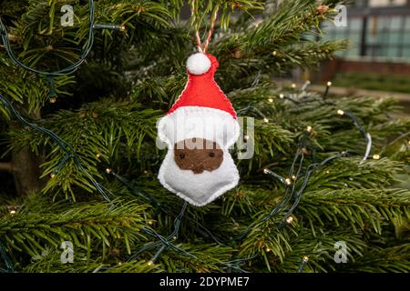 Eine hausgemachte Weihnachtsdekoration, die an einem Weihnachtsbaum hängt In Form einer afrikanischen Weihnachtsklausel Stockfoto