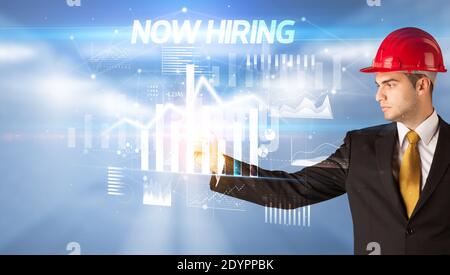 Gut aussehender Geschäftsmann mit Helm Zeichnung JETZT EINSTELLUNG Inschrift, Architektur Konzept Wipl Stockfoto