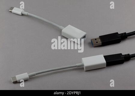 Zwei usb-Kabel und usb-C auf usb-Adapter, ein Satz angeschlossen und das andere getrennt, auf grauem Hintergrund Stockfoto