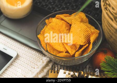 Film zu Hause allein, ungesunde Lebensmittel, Snack, Kartoffelchips in der Schüssel, Laptop, gemütliche Winter Hintergrund Stockfoto
