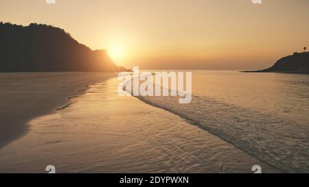 Sonnenuntergang über den Wellen des Ozeans waschen Sandstrand. Luftsonne unterging über Berg Silhouette. Tropic niemand Natur Seestück. Paradiesinsel El Nido, Philippinen, Asien an der Meeresbucht Stockfoto