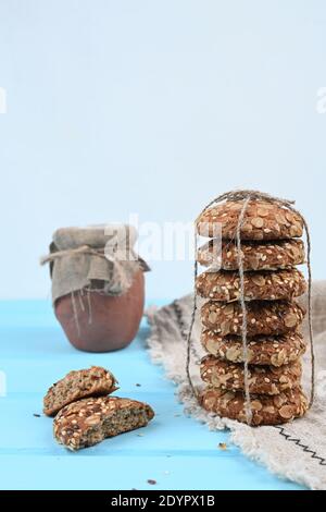 Hausgemachte Haferkekse mit Erdnüssen und Rosinen auf dem Küchentisch, blauer Hintergrund Stockfoto