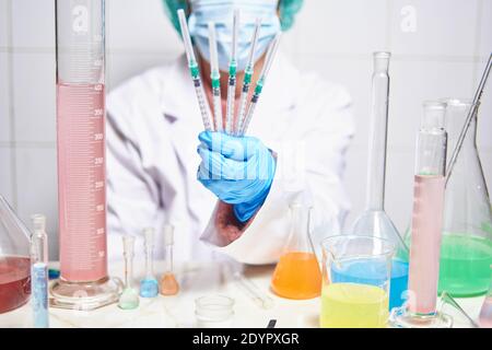 Wissenschaftlerin mit Gesichtsmaske, die im Labor arbeitet und mehrere Impfstoffe gegen das neue Coronavirus covid19 in der Hand hält Stockfoto