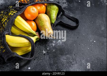 Freundliche Öko wiederverwendbare Beutel mit Früchten. Keine Verschwendung. Nachhaltiges Lifestyle-Konzept. Kunststoff frei. Schwarzer Hintergrund. Draufsicht. Speicherplatz kopieren Stockfoto