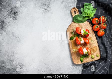 Caprese Salat auf Spieß, Tomaten, Pesto und Mozzarella. Canapes Snack. Grauer Hintergrund. Draufsicht. Speicherplatz kopieren Stockfoto