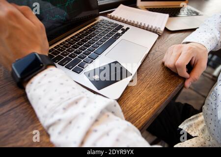 Schwarze Kreditkarte liegt auf grauem Laptop. Schnittansicht des jungen Mannes. Geben Sie Ihre Kreditkartendaten nicht auf verdächtigen Websites ein. Mann mit Kreditkarte zu machen Stockfoto