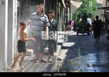 Kinder werden am 6. Juli 2013, drei Tage vor Beginn des Ramadan, dem Fastenmonat für Muslime auf der ganzen Welt, in der Gegend von Bab Al Maqam in Aleppo, Syrien, mit Wasser gewaschen. Foto von Ammar Abd Rabbo/ABACAPRESS.COM Stockfoto