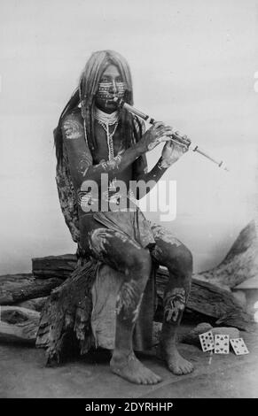 Yuma-Musiker, Arizona. Yuma Mann in Körperfarbe, sitzend, nach vorne gerichtet, Flöte spielen. Stockfoto