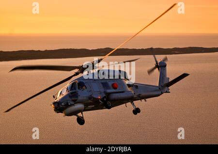 Eine Luft-Luft-Ansicht eines Naval Sikorsky S70B Seahawk Hubschrauber Bank bei Sonnenuntergang. Stockfoto