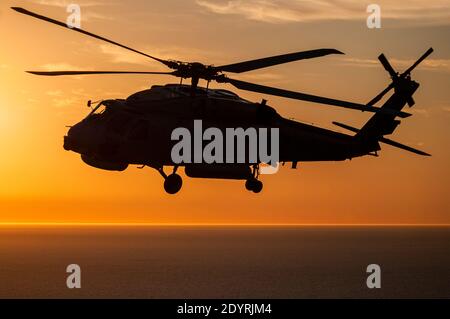 Eine Luft-Luft-Ansicht eines Naval Sikorsky S70B Seahawk Hubschraubers in Silhouette, bei Sonnenuntergang. Stockfoto