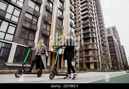 Romantische Datum auf E-Scooter Glückliche Frau mit blonden Haaren und Mann in legerer Kleidung gute Zeit mit dem Fahren auf gemietet Elektro-Scooter und lachen Stockfoto