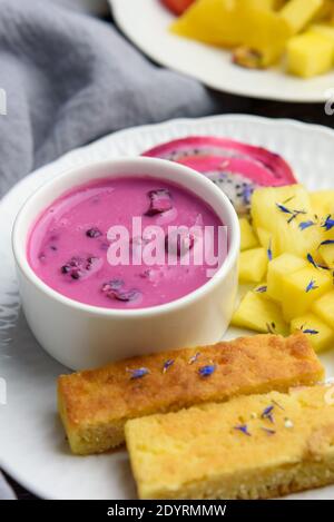 Mangobrot mit Joghurt auf pflanzlicher Basis und frischen Früchten, leuchtende Farben, farbenfrohe Mahlzeit, 45 Grad Winkel, Nahaufnahme Stockfoto