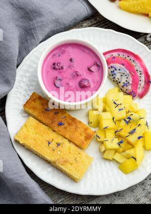 Mangobrot mit Joghurt auf pflanzlicher Basis und frischen Früchten, leuchtenden Farben, farbenfrohem Essen, flacher Lay Stockfoto