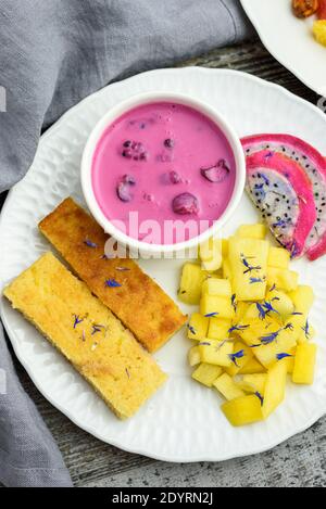 Mangobrot mit Joghurt auf pflanzlicher Basis und frischen Früchten, leuchtende Farben, bunte Mahlzeit, flaches Lay Stockfoto