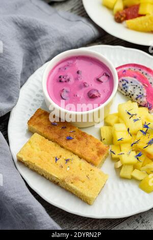 Mangobrot mit Joghurt auf pflanzlicher Basis und frischen Früchten, helle Farben, farbenfrohe Mahlzeit, 45 Grad Winkel Stockfoto